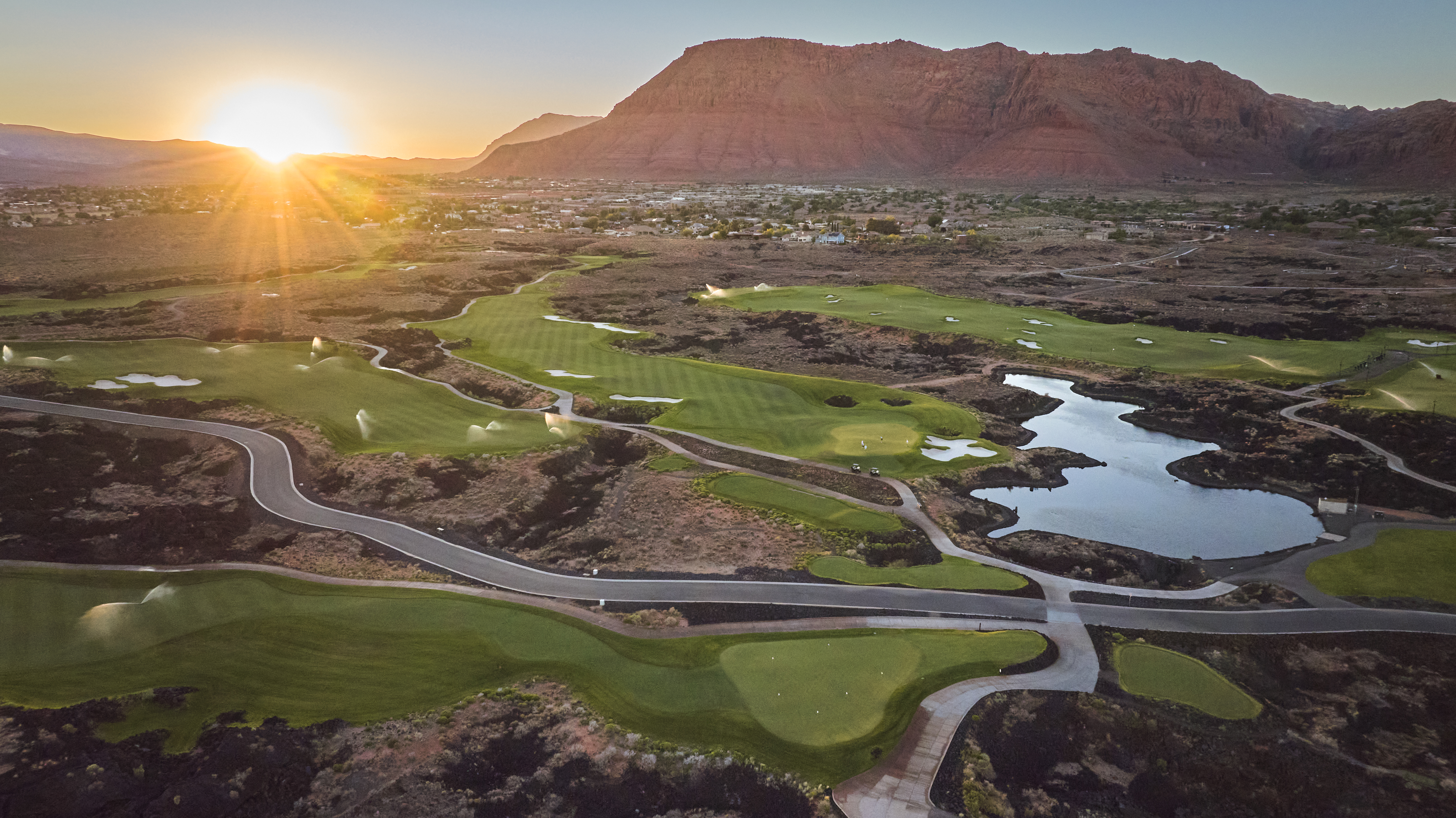 Black Desert Resort fairway with lava rock formations and distant red cliffs in St. George Utah